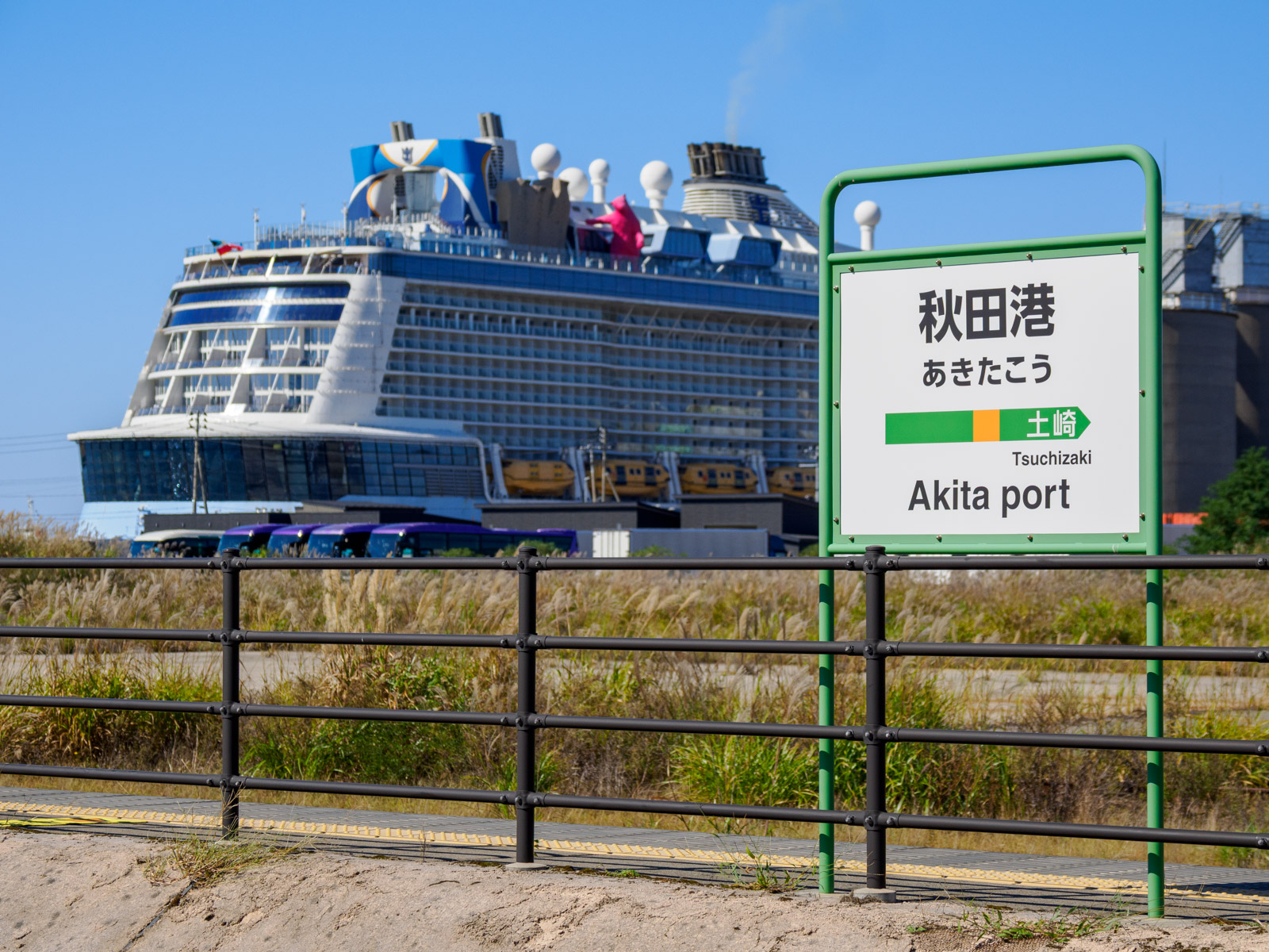 秋田港駅のホームと、秋田港に停泊するクルーズ船「クアンタム・オブ・ザ・シーズ」(2024年10月)