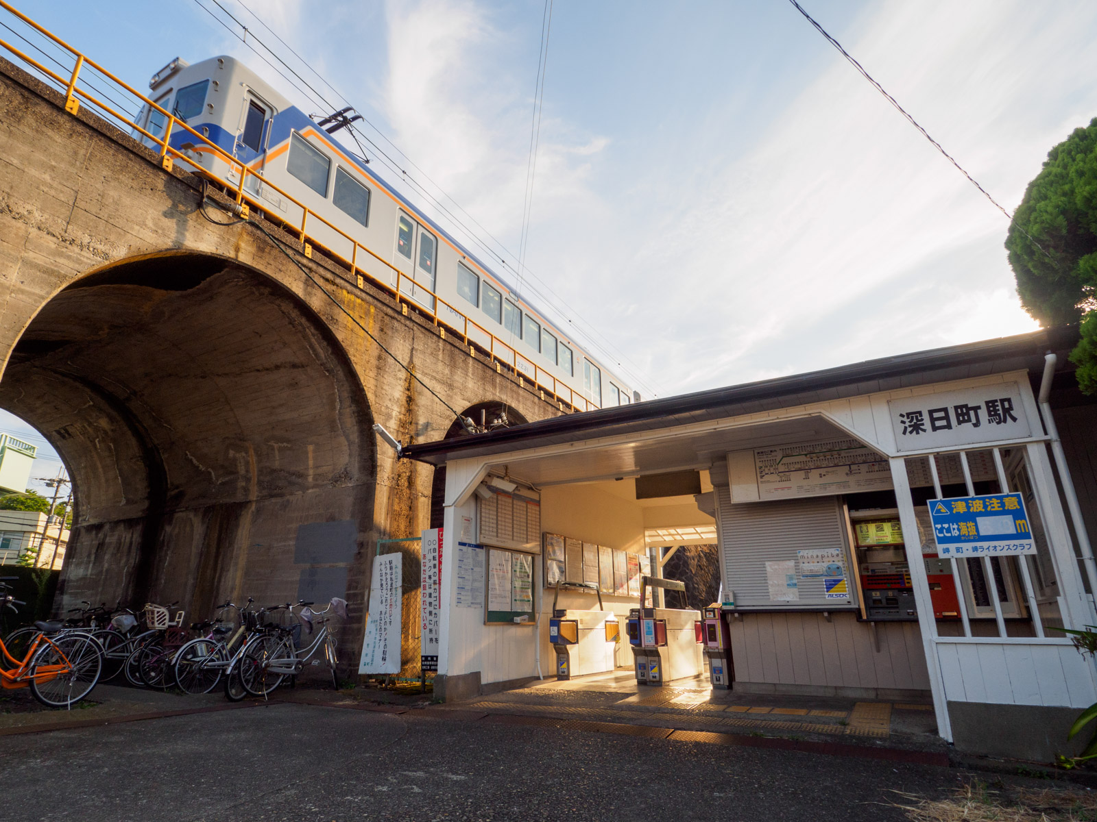 深日町駅の駅舎、アーチ橋と列車（2016年8月）