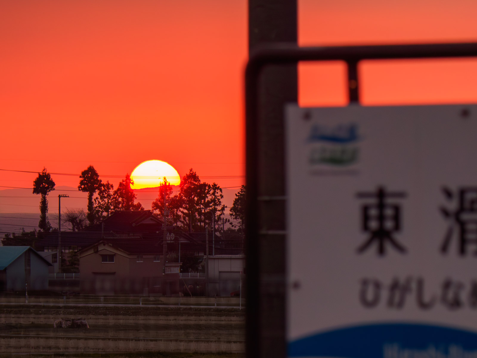 東滑川駅の駅名標と、能登半島に沈む夕日（2024年4月）