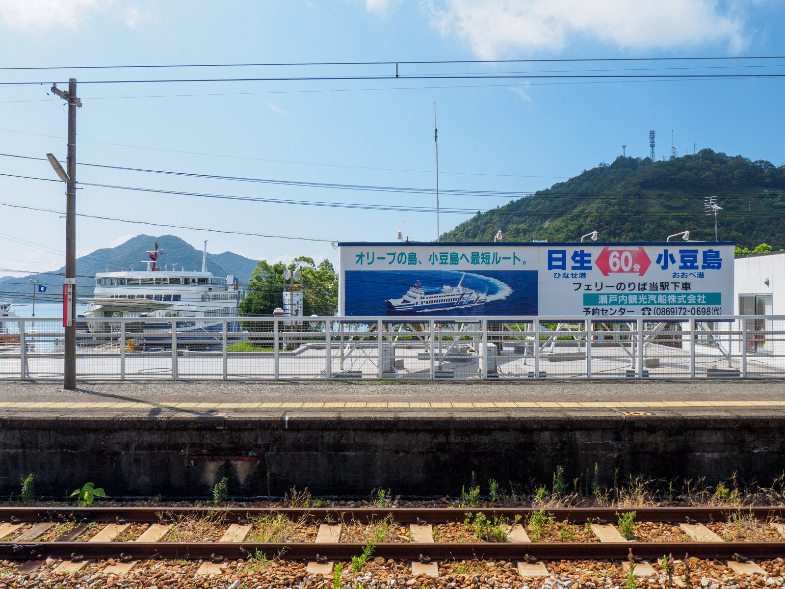 日生駅のホームから見た、小豆島行きのフェリーと航路の看板（2023年9月）