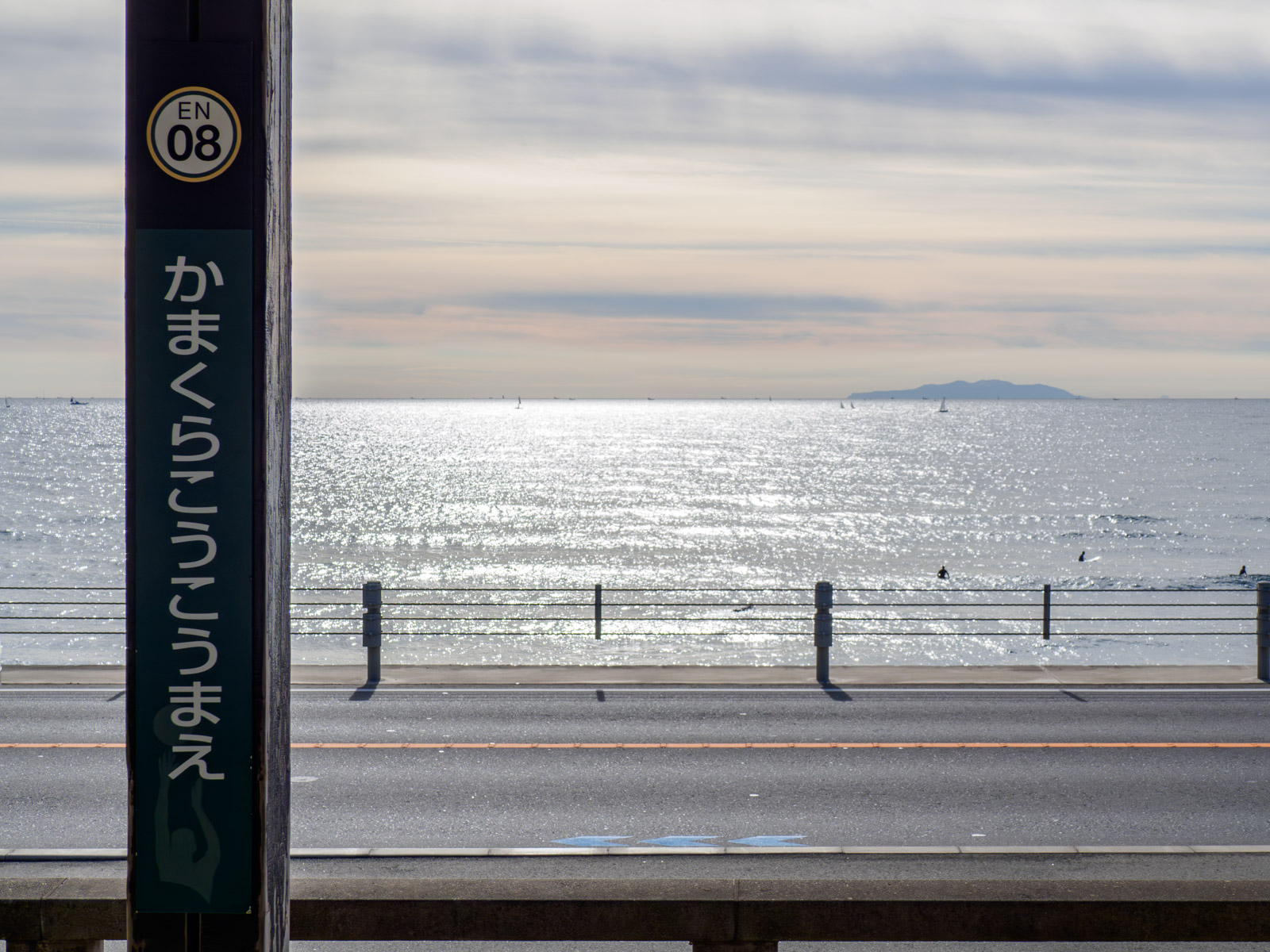 鎌倉高校前駅の駅名標と、ホームから見た伊豆大島（2022年1月）