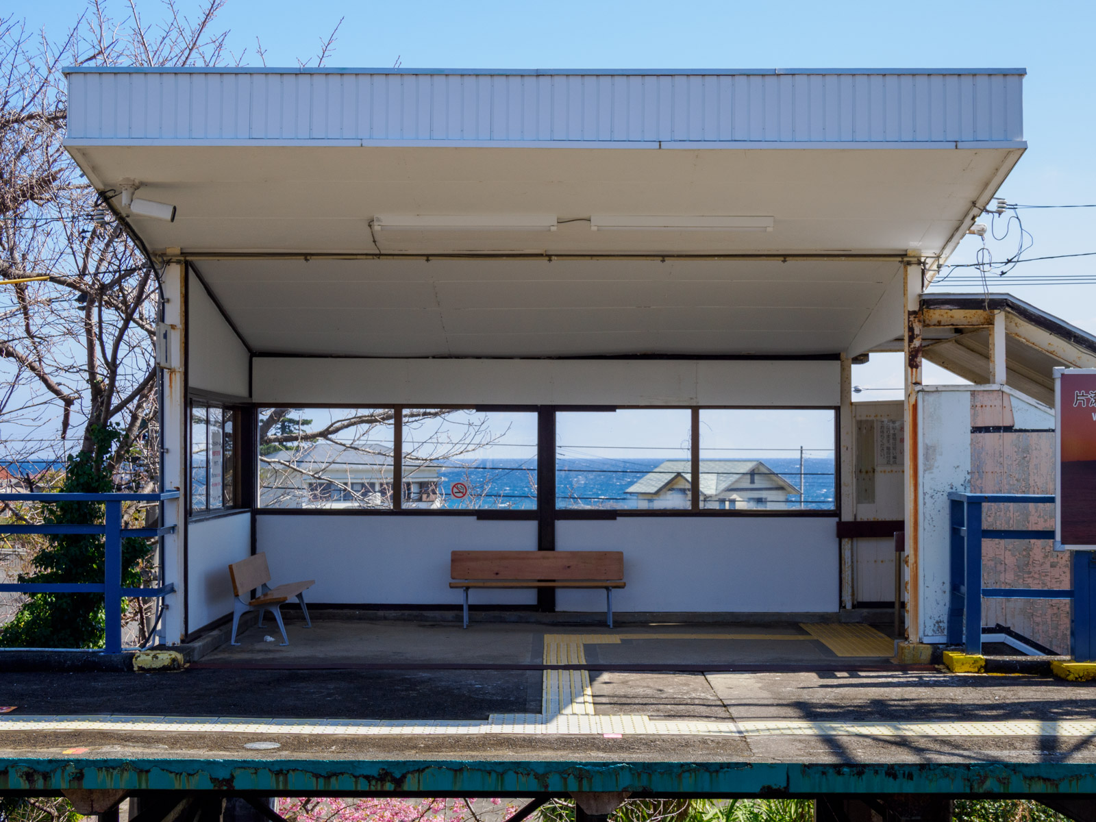 片瀬白田駅のホームにある待合室と、窓越しの相模灘(2025年3月)
