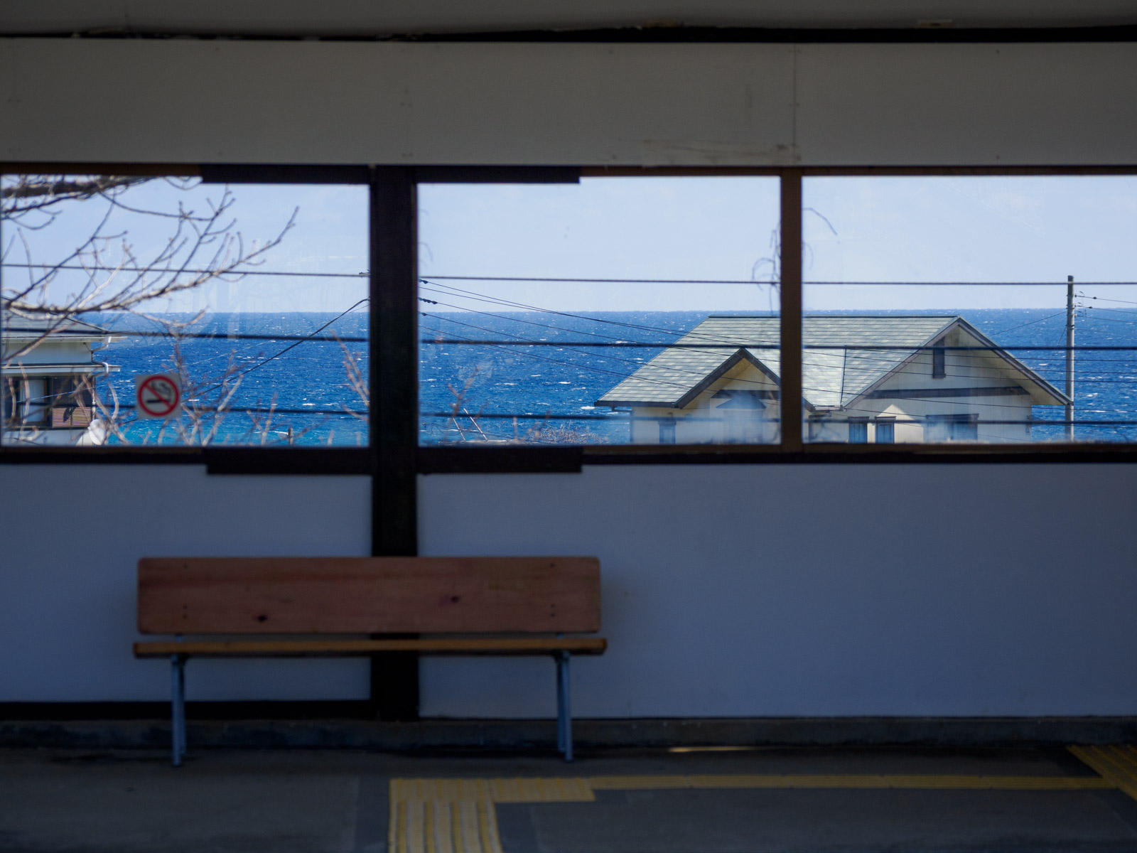 片瀬白田駅のホームにある待合室と、窓越しの相模灘(2025年3月)