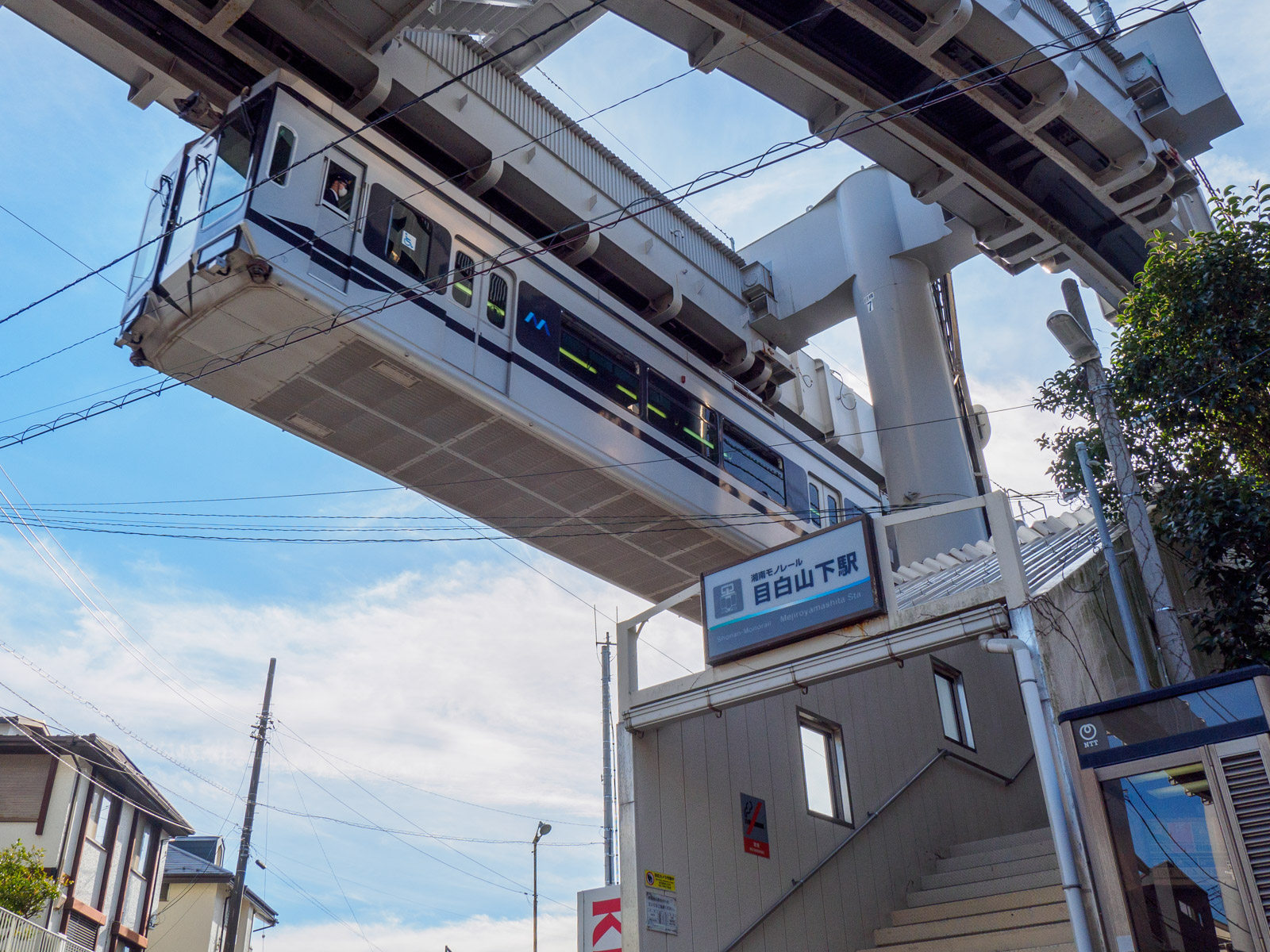 目白山下駅の入口と、頭上を通る列車（2022年1月）