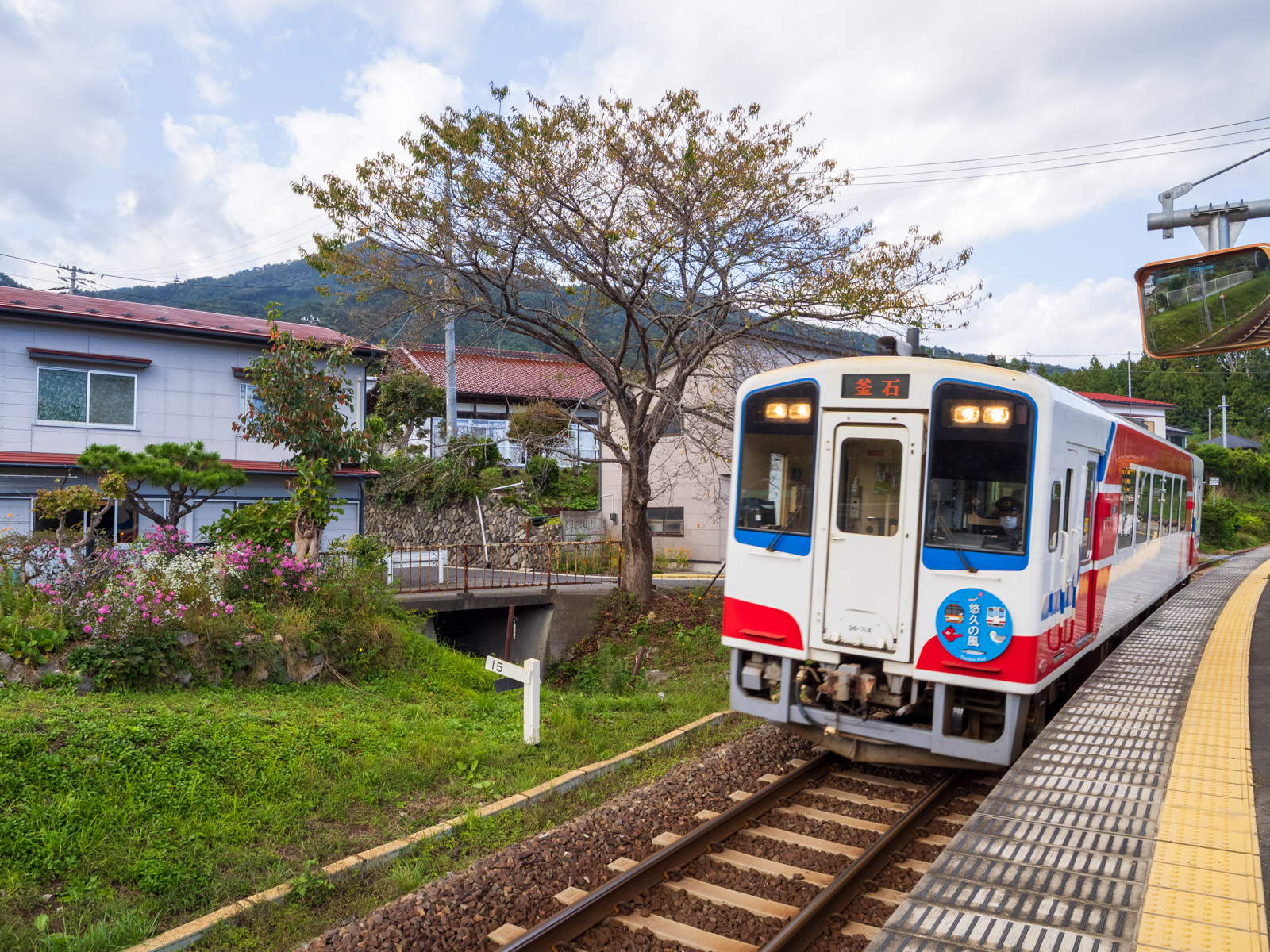 浪板海岸駅に到着する列車と、山側の集落(2024年10月)