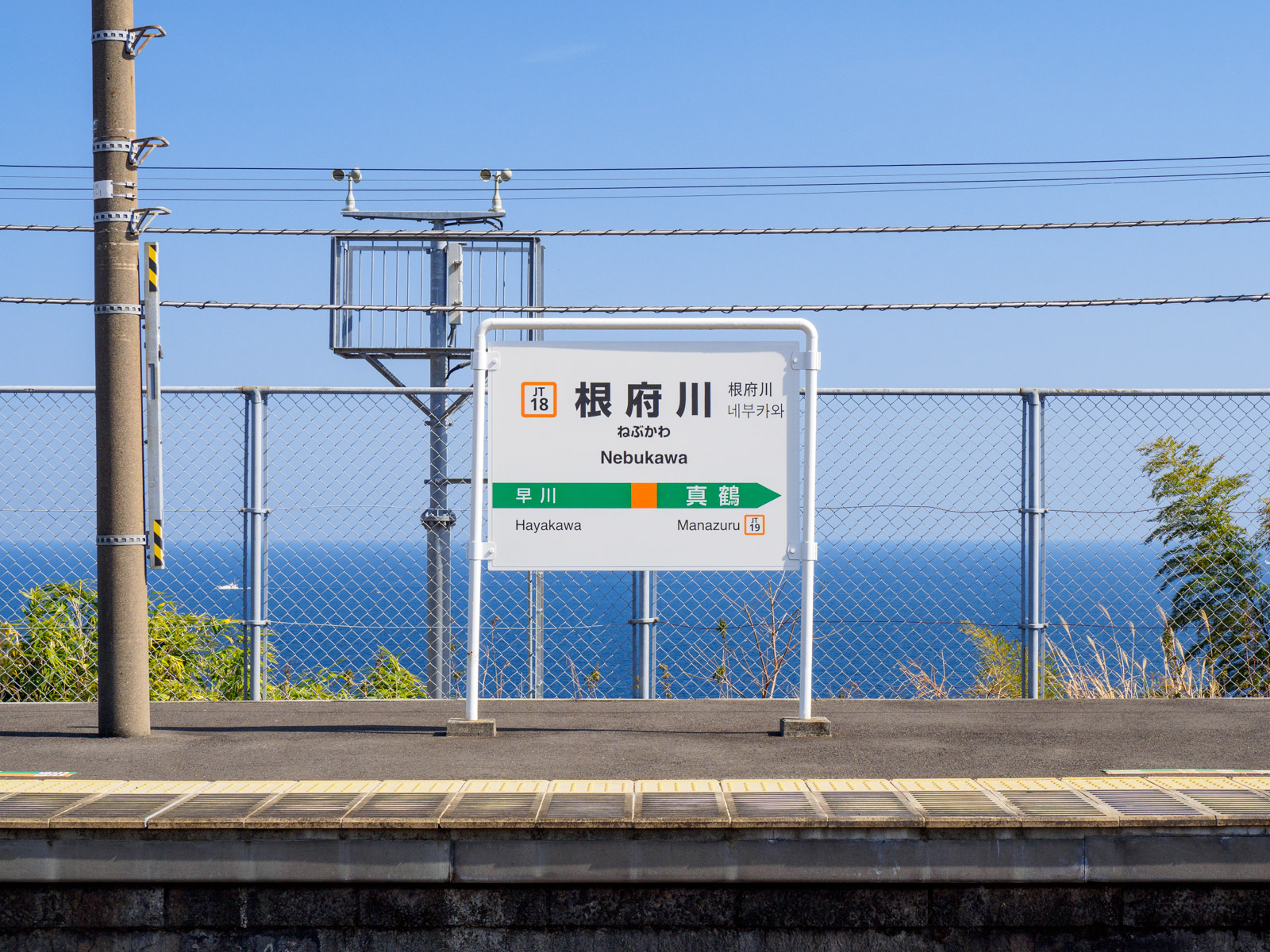 根府川駅の駅名標と、相模湾の水平線（2022年3月）