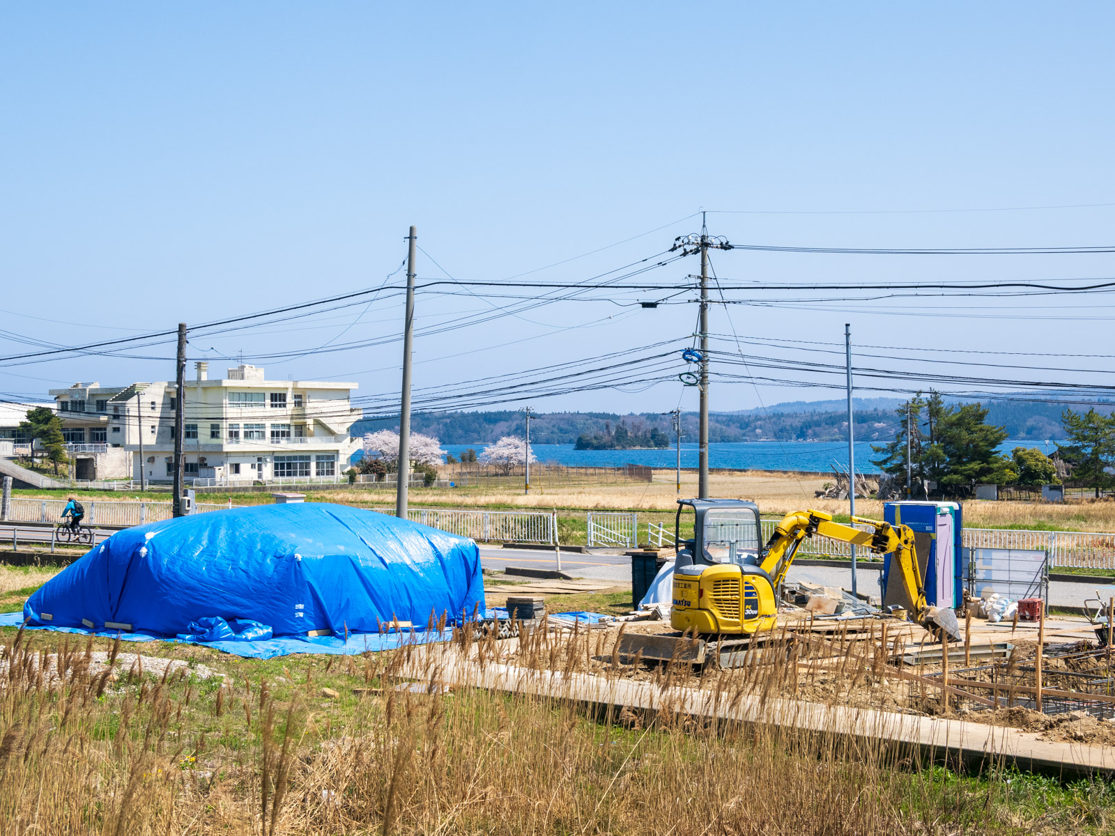 西岸駅のホームから見た七尾湾と、建て替え中の民家(2025年4月)