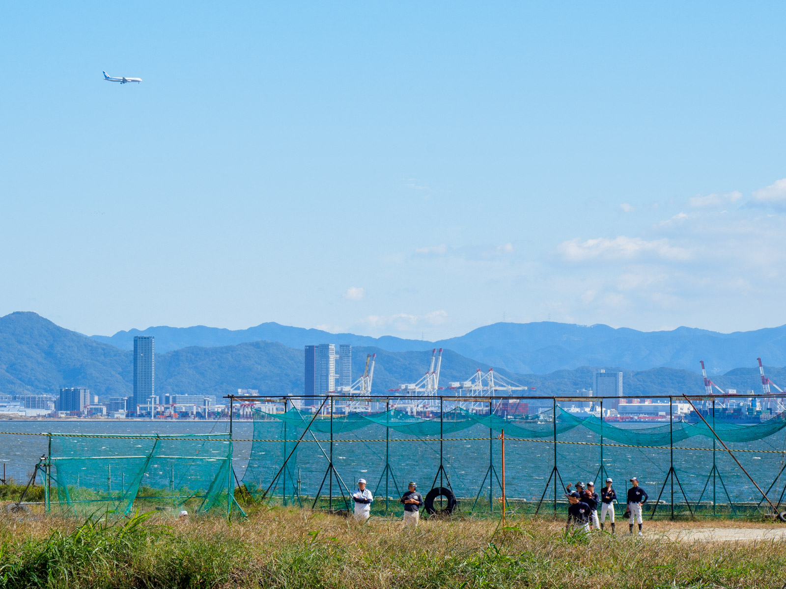 西戸崎駅のホームから見た、野球場と博多湾、福岡空港に着陸する飛行機（2022年10月）