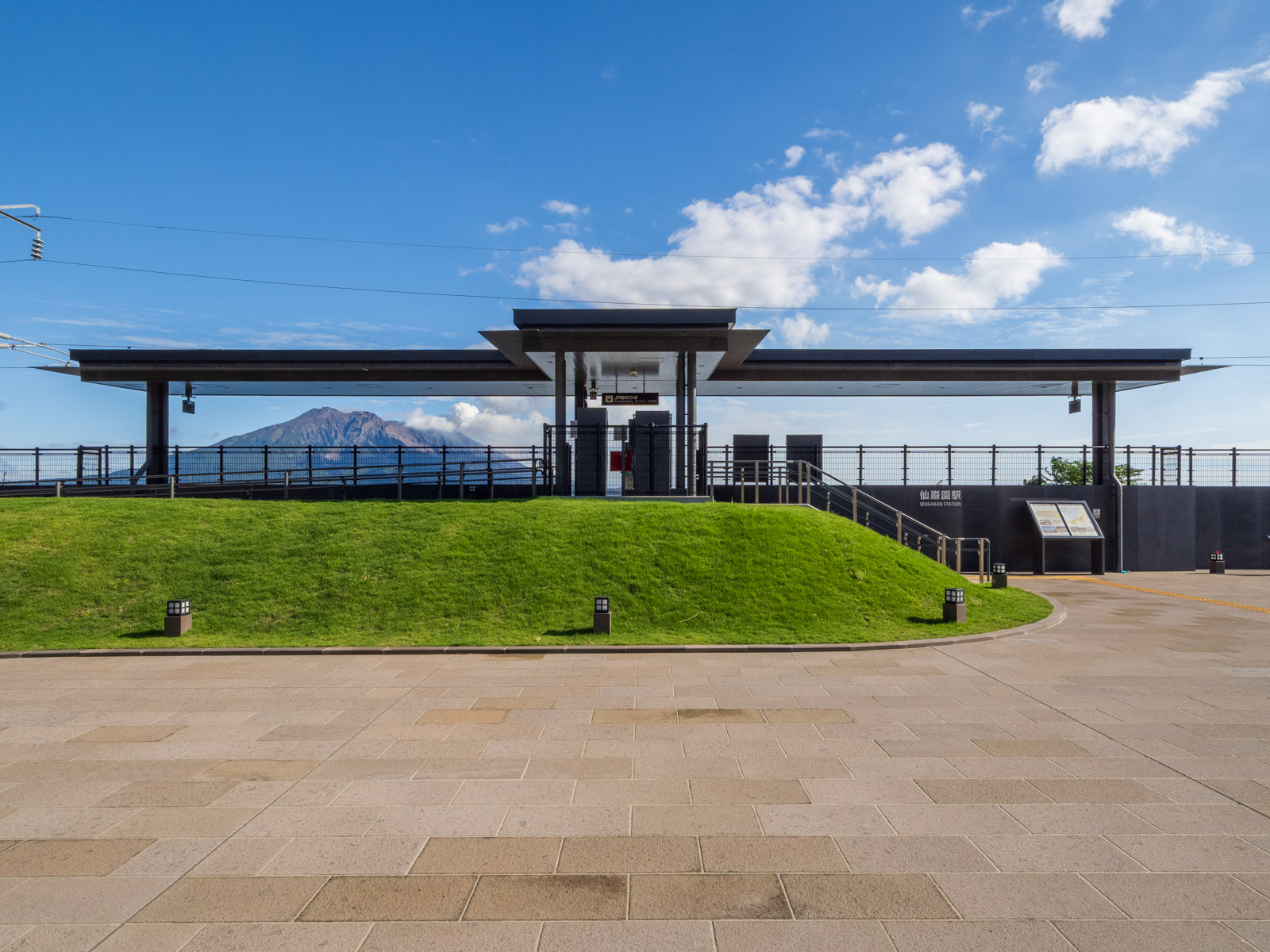 仙巌園駅の外観と、駅越しの桜島（2025年10月）