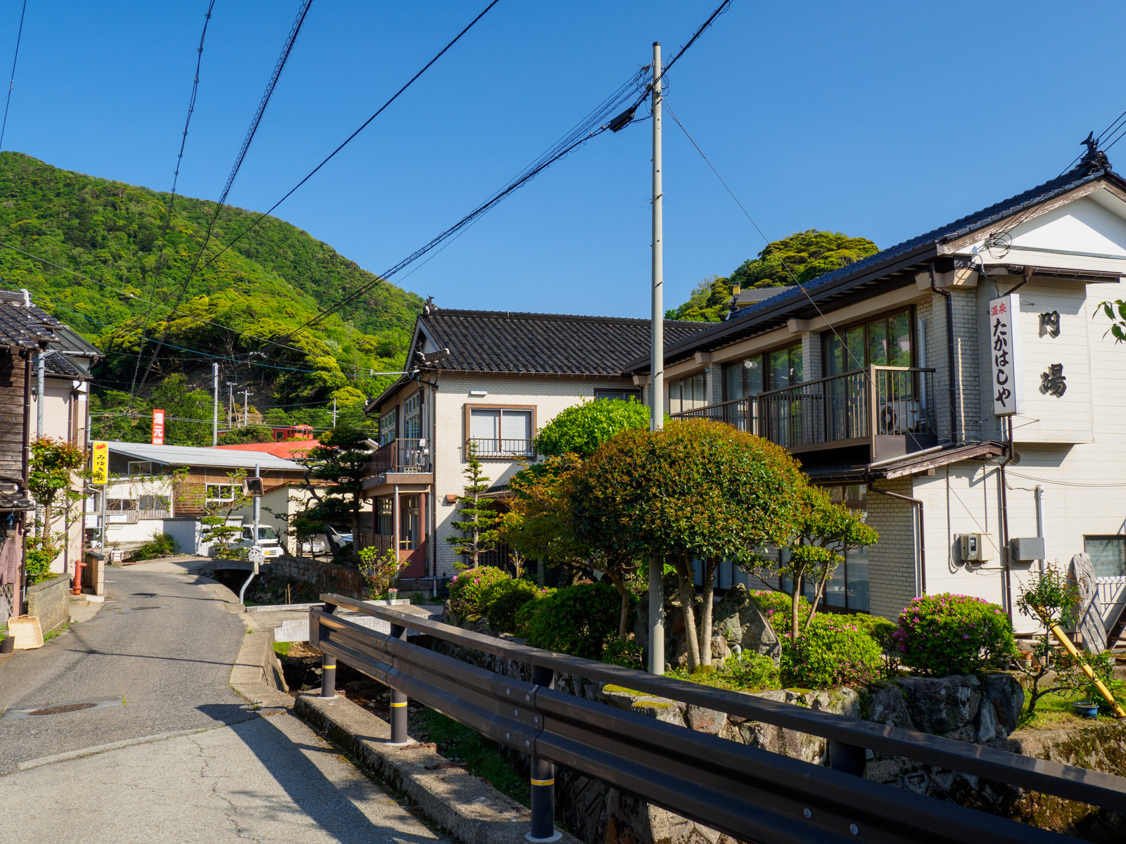 柴山駅のそばにある民宿と、柴山駅を発つ列車（2022年5月）