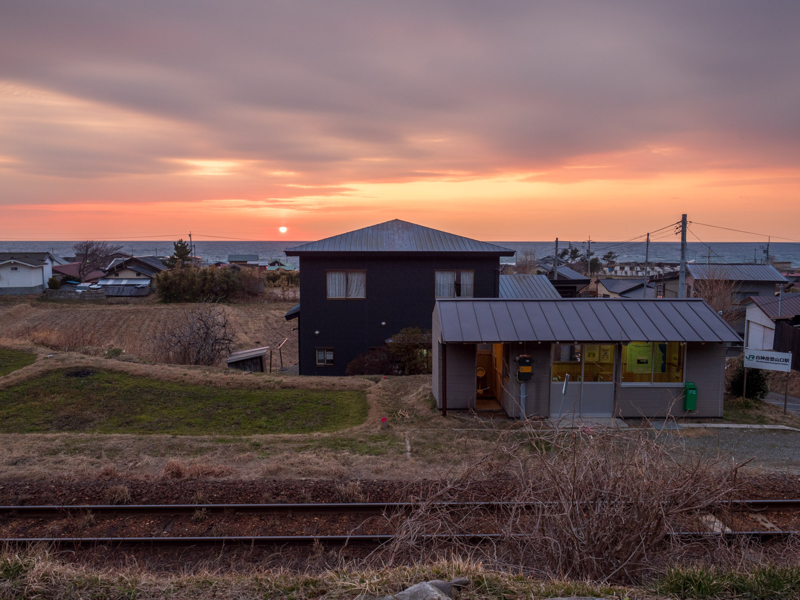 国道101号から見た、白神岳登山口駅と夕暮れの日本海（2016年3月）