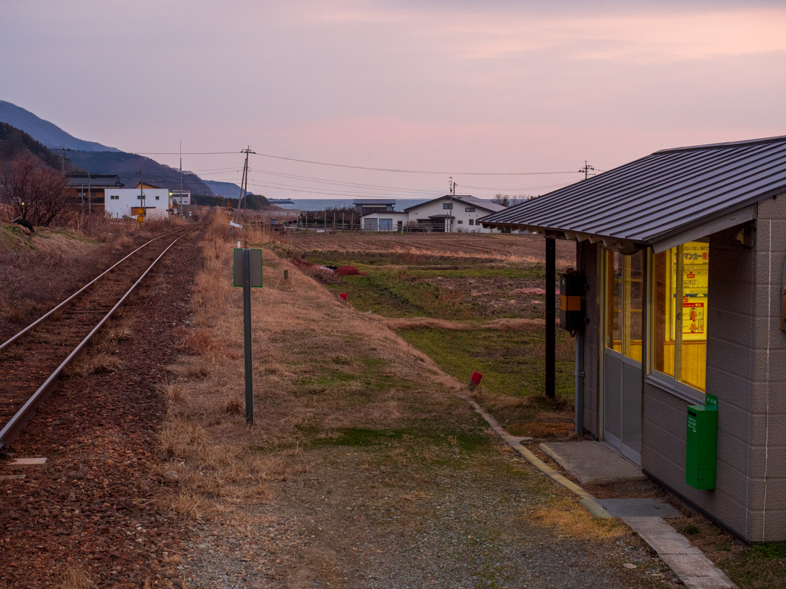 白神岳登山口駅の待合室と、線路の先に見える海（2016年3月）