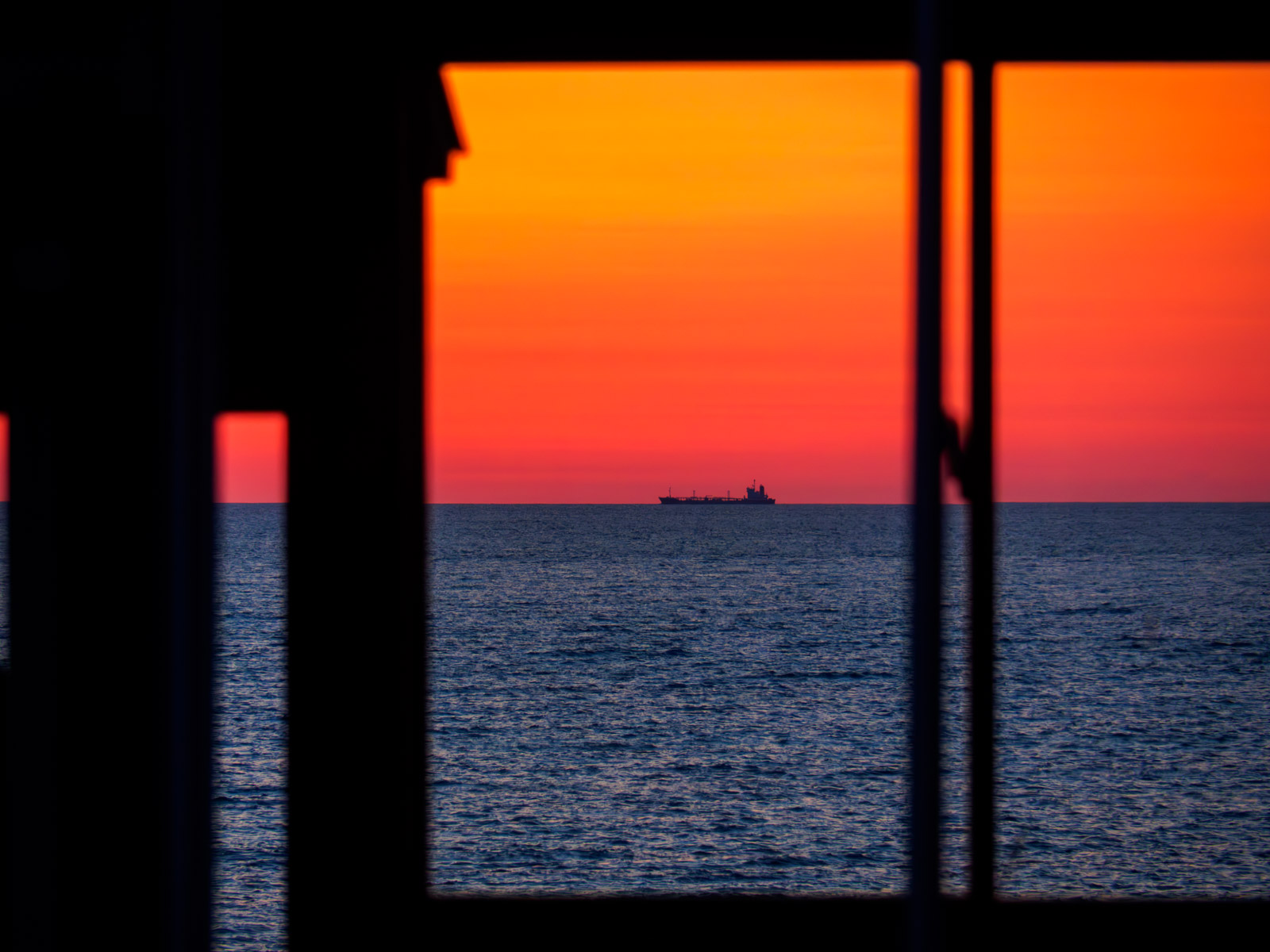 驫木駅の駅舎の窓越しに見た、夕暮れの日本海と船（2017年5月）