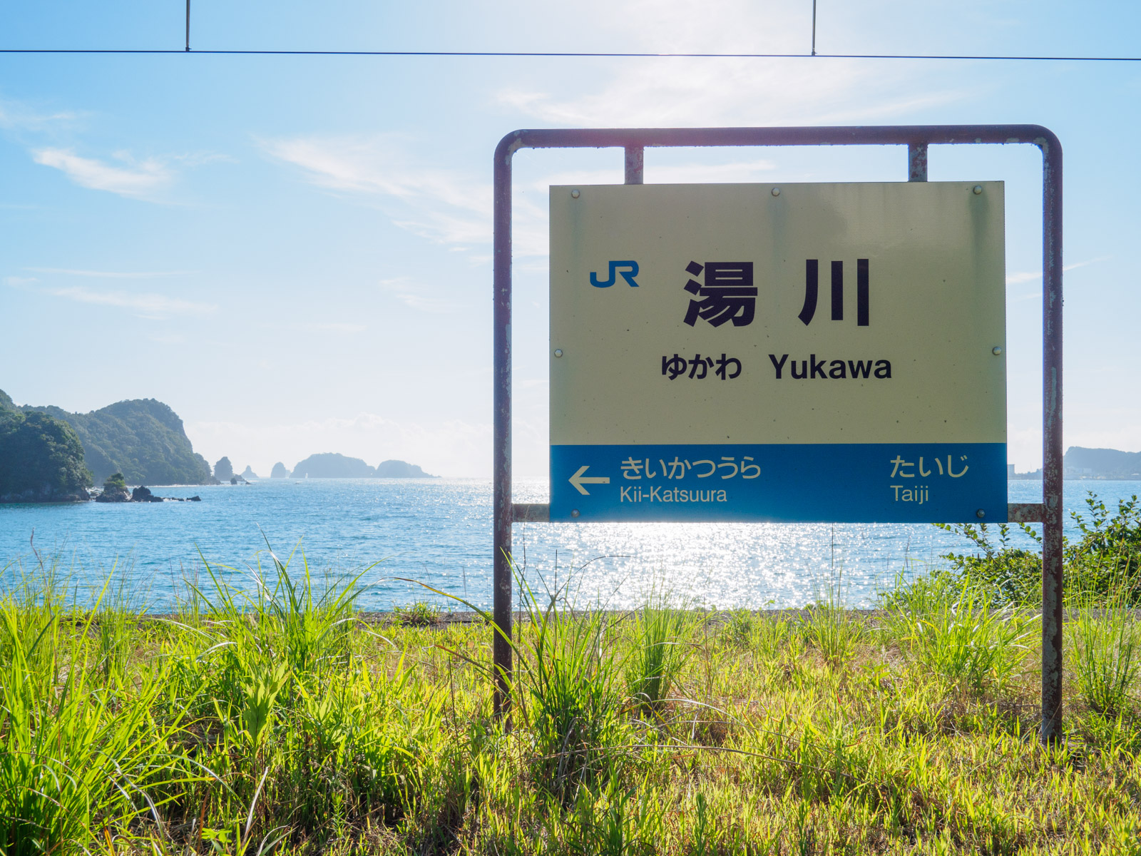 湯川駅の駅名標と、ホームから見た太平洋と紀の松島（2016年8月）