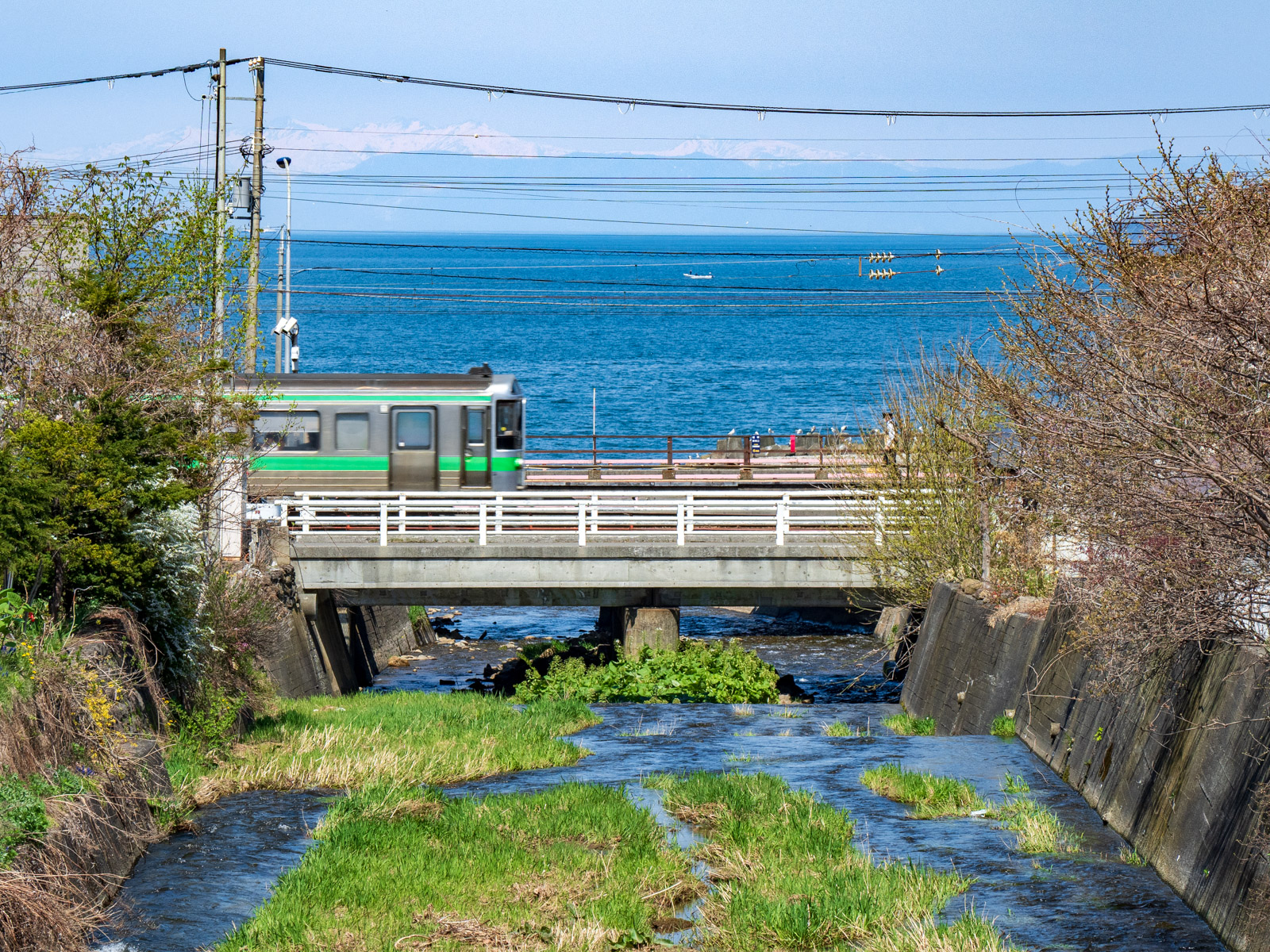 銭函川に架かる橋から見た、銭函駅と石狩湾（2024年5月）
